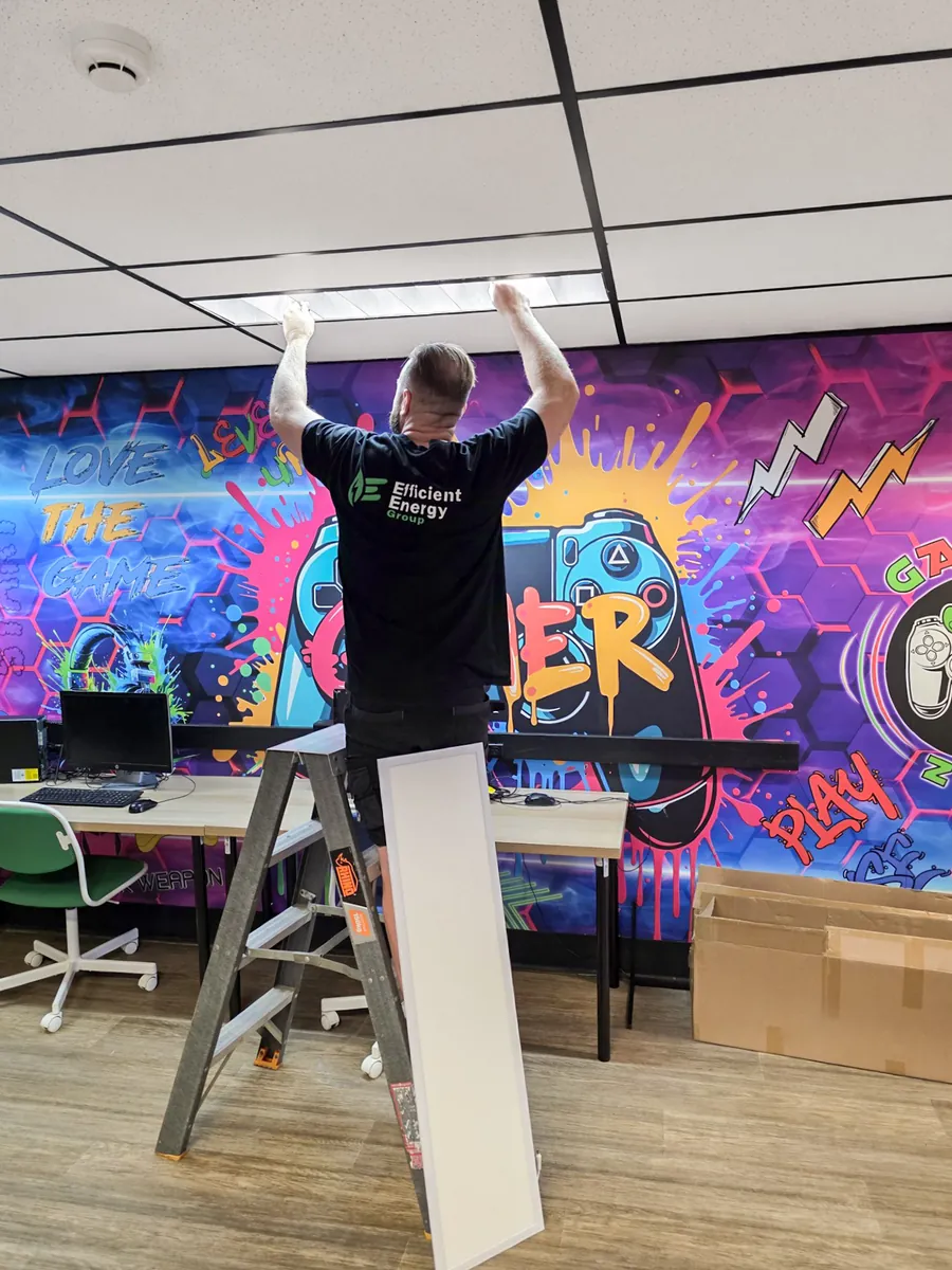 Efficient Energy Group electrician removing old fluorescent tubes from an office ceiling during an LED panel upgrade in Sydney